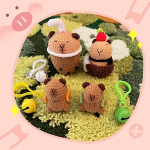 May include: Four brown crocheted amigurumi animal figurines, each with a different design. The figurines are sitting on a green and brown textured surface.