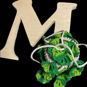 May include: A wooden letter M with a green and white crocheted ball of yarn with a white string attached.