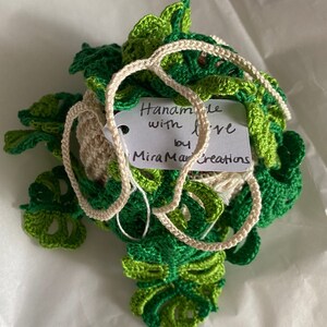 May include: A crocheted green and white plant with a tag that reads "Handmade with love by MiraMar Creations".