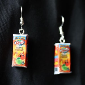 May include: Two silver earrings with miniature juice boxes hanging from them. The juice boxes are red, orange, and yellow with the words 