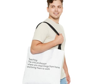 May include: A white tote bag with black straps and the text "Teaching. The only profession where you steal things from home and bring them to work." A person is holding the bag.