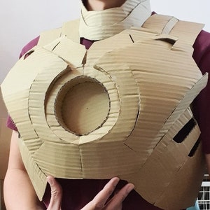 May include: A cardboard chest piece costume, resembling the Iron Man suit, with a circular opening in the center.