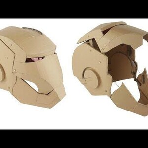 May include: A cardboard Iron Man helmet, shown in two views. The helmet is made of brown cardboard and has a detailed design. The helmet is partially assembled, showing the inner structure.