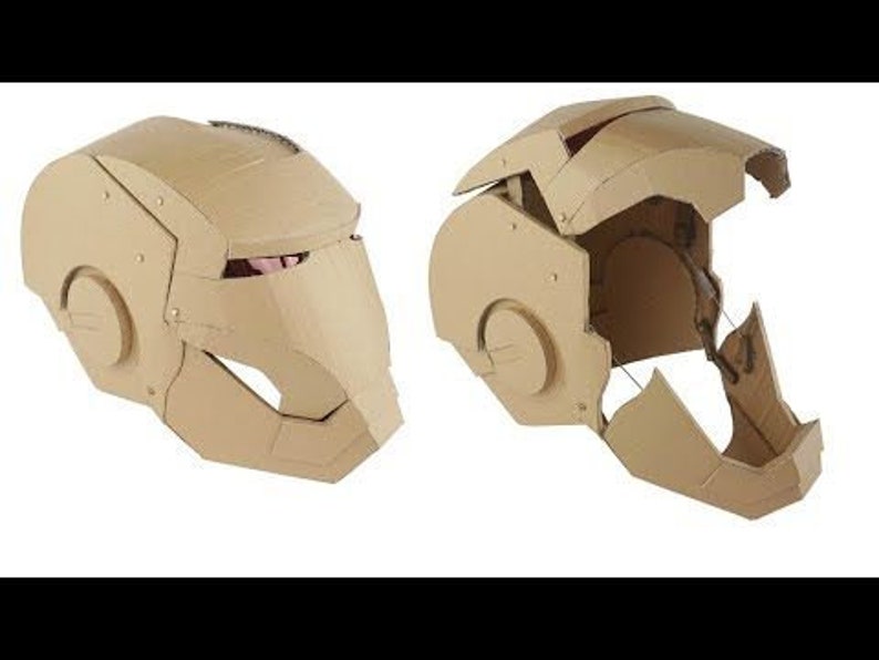 May include: A cardboard Iron Man helmet, shown in two views. The helmet is made of brown cardboard and has a detailed design. The helmet is partially assembled, showing the inner structure.