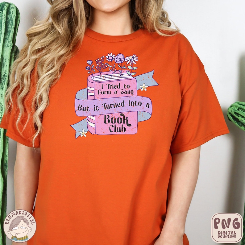 Puede incluir: Camiseta naranja con un gr&aacute;fico de libro rosa. El libro tiene el texto "I Tried to Form a Gang But it Turned Into a Book Club".