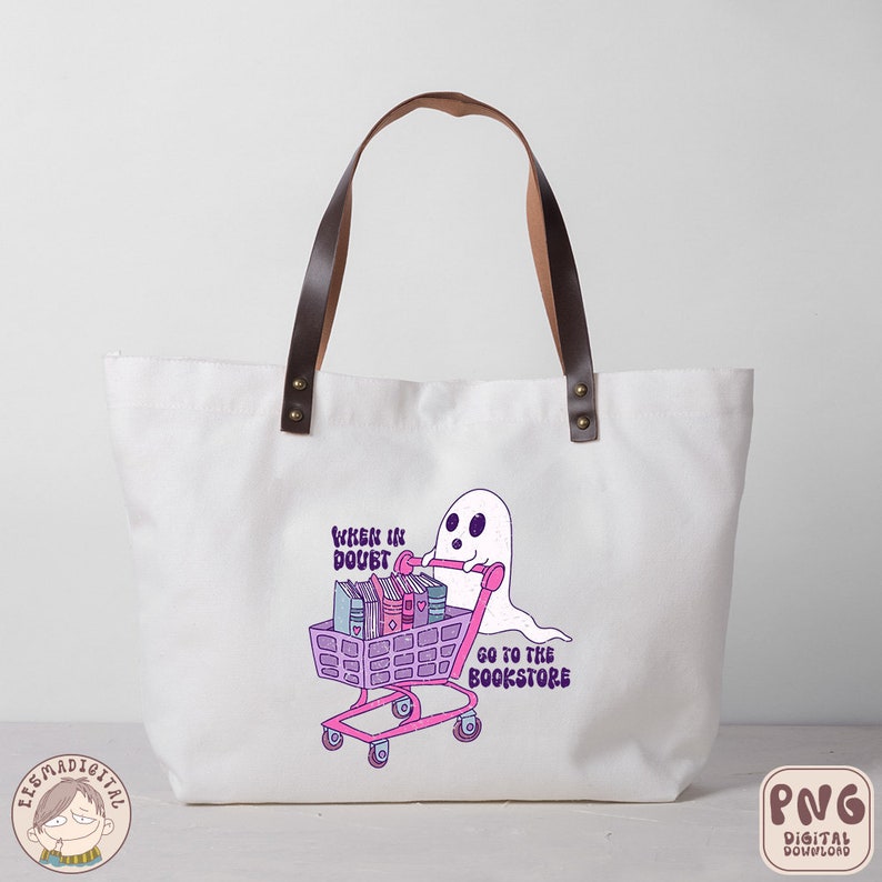 K&ouml;nnte beinhalten: Eine wei&szlig;e Einkaufstasche mit braunen Ledergriffen. Die Tasche hat ein pinkfarbenes und violettes Design mit einem Geist, der einen Einkaufswagen voller B&uuml;cher schiebt. Der Text auf der Tasche lautet "When in doubt, go to the bookstore".