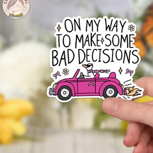 May include: A pink car with a white goose wearing a scarf driving. The car has flames coming out of the back. The text on the sticker says "On my way to make some bad decisions".