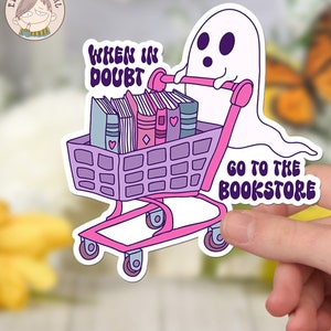K&ouml;nnte beinhalten: Ein rosa und lila Einkaufswagen voller B&uuml;cher wird von einem wei&szlig;en Geist geschoben. Der Wagen tr&auml;gt den Text "WHEN IN DOUBT GO TO THE BOOKSTORE".