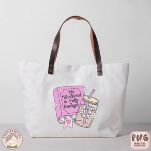 May include: A white tote bag with brown leather handles. The bag has a pink book with the text "My Weekend is Fully Booked" and a glass of iced coffee with a straw.