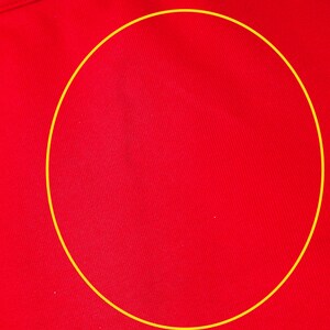 May include: Close-up of a vibrant red fabric with a subtle texture. The fabric appears to be part of a garment, with a white collar visible at the top. The material has a smooth, slightly shiny appearance.