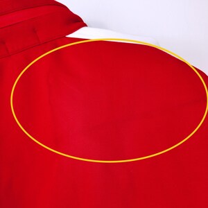 May include: A close-up of a red collared shirt hanging on a white hanger. The shirt is a solid, vibrant red color, with a smooth, slightly shiny texture. The collar is visible, and the shirt appears to be made of a lightweight fabric.