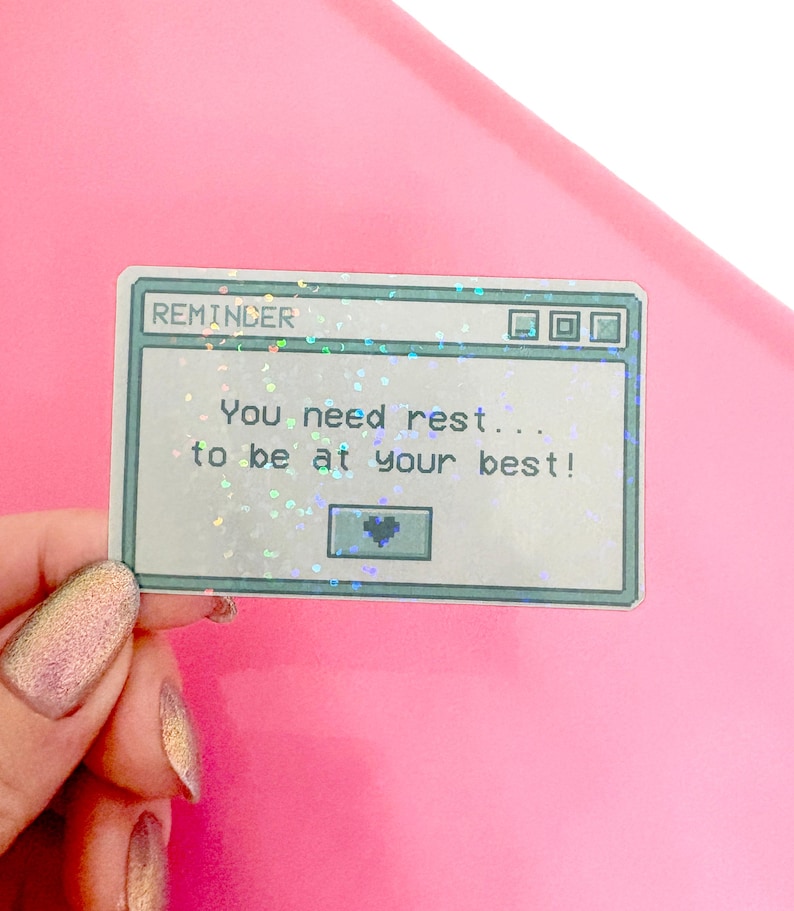 Peut inclure: Un autocollant holographique avec un design d'&eacute;cran d'ordinateur pix&eacute;lis&eacute;. L'&eacute;cran affiche le texte "REMINDER You need rest... to be at your best!" avec une petite ic&ocirc;ne de c&oelig;ur dans le coin inf&eacute;rieur droit.