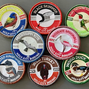 May include: Nine embroidered patches featuring different birds, each with a month, bird name, and "Holy City Birding" text. The patches are circular and have a white background with colorful borders.