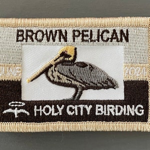 May include: A brown and white embroidered patch with a brown pelican, the text "BROWN PELICAN", "JUNE 2024", and "HOLY CITY BIRDING".