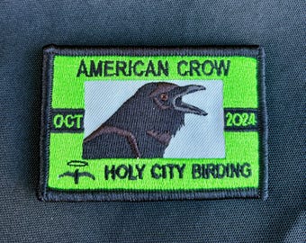 May include: Green and black embroidered patch with the text "AMERICAN CROW" and "HOLY CITY BIRDING" with a black crow illustration in the center. The patch also includes the text "OCT" and "2024".