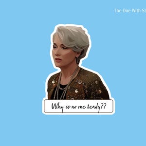 May include: A sticker featuring a stylized illustration of a woman with short, gray hair, wearing a patterned jacket and multiple necklaces. The text "Why is no one ready??" is below the image. The background is light blue.