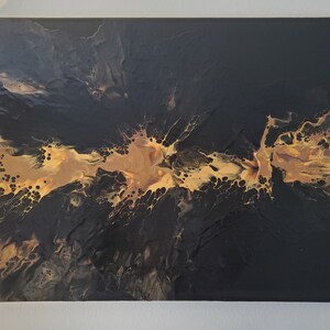 Puede incluir: Pintura abstracta con fondo negro y un diseño de salpicaduras doradas y fluidas.
