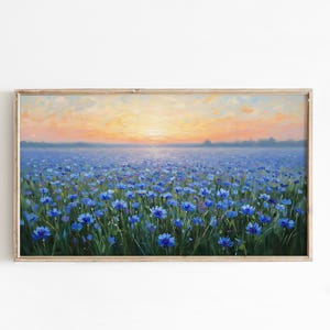Puede incluir: Una pintura de paisaje enmarcada representa un campo de flores azules bajo un cielo de puesta de sol. La obra de arte presenta una vibrante exhibición de flores azules, con una cálida luz dorada que ilumina el horizonte. La pintura está encerrada en un marco de madera.