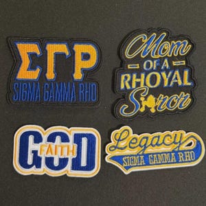 May include: Four embroidered patches with text in blue, yellow, and white. The patches include the phrases "ΣΓΡ SIGMA GAMMA RHO", "Mom of a Rhoyal Soror", "GOD FAITH", and "Legacy SIGMA GAMMA RHO".