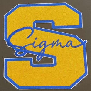 May include: A yellow and blue embroidered patch in the shape of the letter "S". The letter is outlined in blue with a white border. The word "Sigma" is embroidered in blue cursive across the center of the letter.