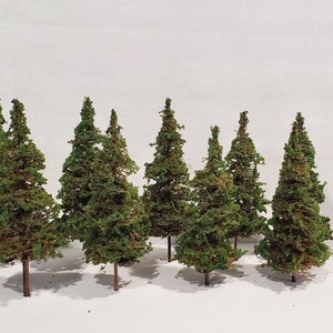 May include: A set of nine miniature evergreen trees, perfect for model railroading or miniature landscaping. The trees are made of a green, brown, and tan material and are approximately 3 inches tall.