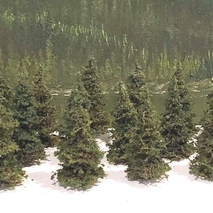 Puede incluir: Colección de árboles de hoja perenne en miniatura, de altura variable, con un aspecto texturizado, verde y marrón. Los árboles están dispuestos en un grupo, adecuados para maquetas de paisajes o proyectos de manualidades. Una regla está en el fondo.