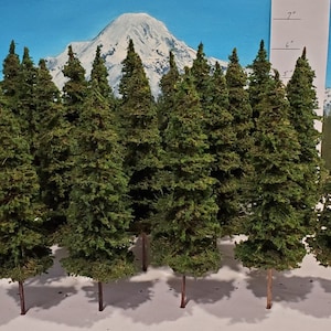 Puede incluir: Un conjunto de 12 árboles de hoja perenne en miniatura, perfectos para el modelismo ferroviario o la jardinería en miniatura. Los árboles están hechos de flocado verde y tienen tallos de alambre marrón. Miden aproximadamente 18 cm de alto.