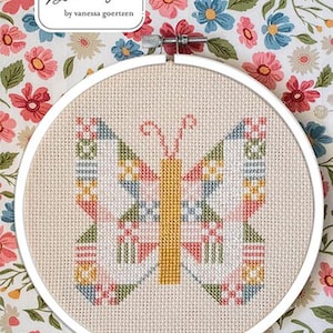 May include: A cross-stitch butterfly design in a white hoop. The butterfly features a colorful geometric pattern in pink, blue, yellow, and green. The background is a floral pattern. The text "Lella Boutique" and "Butterfly Patch" are visible.