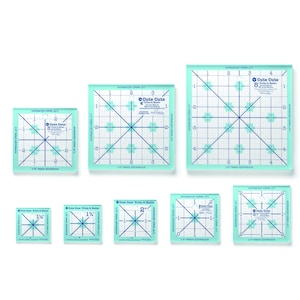 May include: A collection of clear, square quilting rulers in various sizes. Each ruler features a grid pattern with blue markings and the text "Cute Cuts". Measurements are in inches, with sizes ranging from 1.5" to 5".