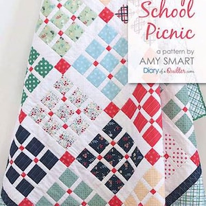 May include: A patchwork quilt with a vibrant design of squares and diamonds in shades of red, blue, green, and cream. The quilt has a white backdrop and a border with a green and blue plaid pattern. The text "Prep School Picnic" is visible.