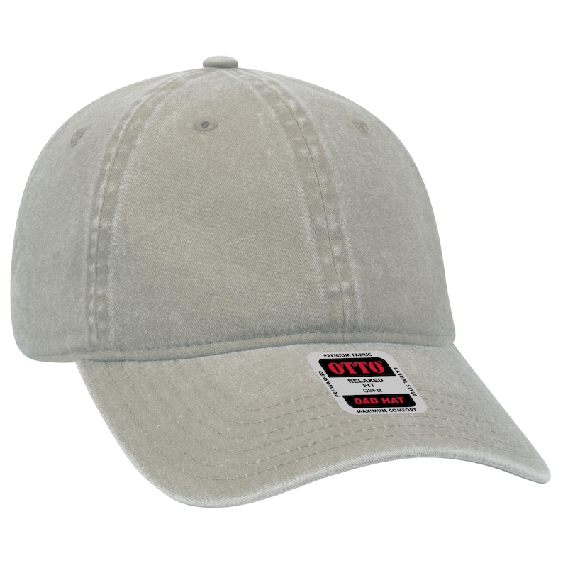 May include: A light gray cotton dad hat with a relaxed fit. The hat has a curved brim and a label that reads "Otto Premium Fabric Relaxed Fit Dad Hat Maximum Comfort".