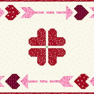 Peut inclure: Une courtepointe rectangulaire avec un fond crème et une bordure rouge. La courtepointe présente quatre grands motifs en forme de cœur rouges et une bordure de flèches et de cœurs roses et bordeaux. Les cœurs ont un motif pointillé.
