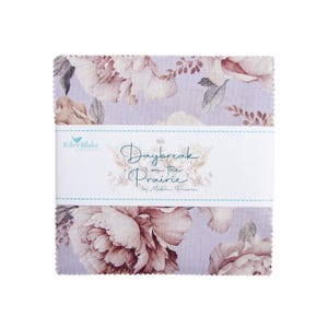 Könnte beinhalten: Ein Stapel Stoffquadrate mit einem floralen Muster in Lila-, Rosa- und Brauntönen. Das Gewebe ist mit einem weißen Band umwickelt, auf dem "Daybreak on the Prairie" von Moda Prairie und das Riley Blake Designs-Logo steht.