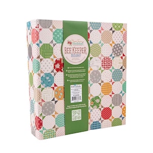 May include: A three-ring binder featuring a colorful patchwork quilt pattern of octagonal shapes in various floral and geometric prints. A green vertical band wraps around the center with the text Bee Keeper Binder and Riley Blake Designs.