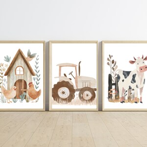 May include: Three framed watercolor prints featuring farm animals and objects. The prints include a chicken coop with chickens, a tractor, and a cow. The artwork has a neutral color palette with brown, beige, and green accents, and is set against a white background.