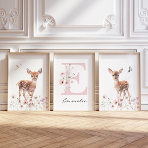 May include: Three framed prints with a pink floral and deer theme. The centre print features a large pink letter E with the name Emmalee below it. The left and right prints feature a watercolour illustration of a fawn standing in a field of flowers.