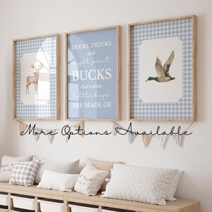 May include: Three framed prints with a woodland theme. One features a deer, another a duck, and the third has text that reads "DUCKS, TRUCKS and eight point BUCKS that's what little boys ARE MADE OF". The frames are light wood.