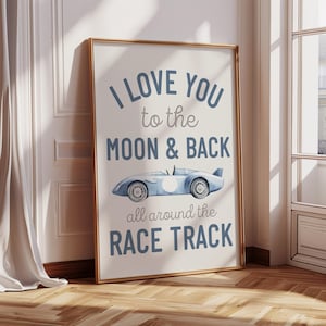 May include: A framed print with the text "I LOVE YOU to the MOON & BACK all around the RACE TRACK". The image shows a light blue race car illustration. The frame is gold. The print is leaning against a wall.