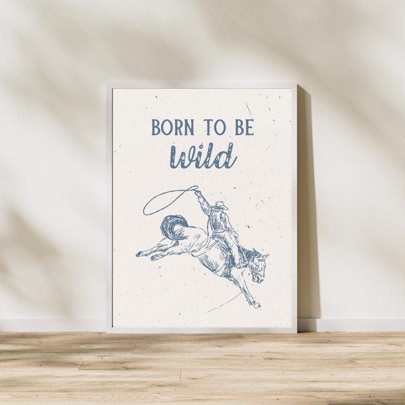 K&ouml;nnte beinhalten: Ein wei&szlig;er gerahmter Druck mit dem Text "Born to be wild" in blauer Schrift. Unter dem Text befindet sich eine blaue Strichzeichnung eines Cowboys, der ein buckelndes Pferd reitet.