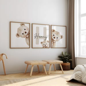 Puede incluir: Tres impresiones enmarcadas con osos de peluche de acuarela y el nombre "Henry". Las impresiones tienen una paleta de colores neutros con marcos dorados. La habitaci&oacute;n tambi&eacute;n incluye dos peque&ntilde;os bancos de madera y una planta en maceta.