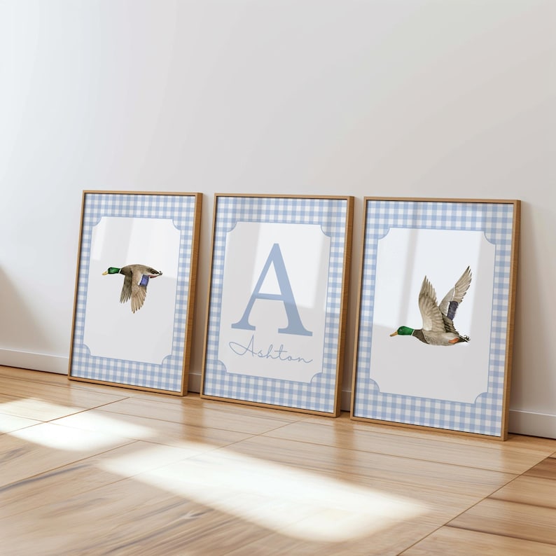 May include: Three framed prints with a blue and white gingham pattern. The center print features the letter A and the name Ashton. The prints on either side feature a watercolor illustration of a duck in flight.