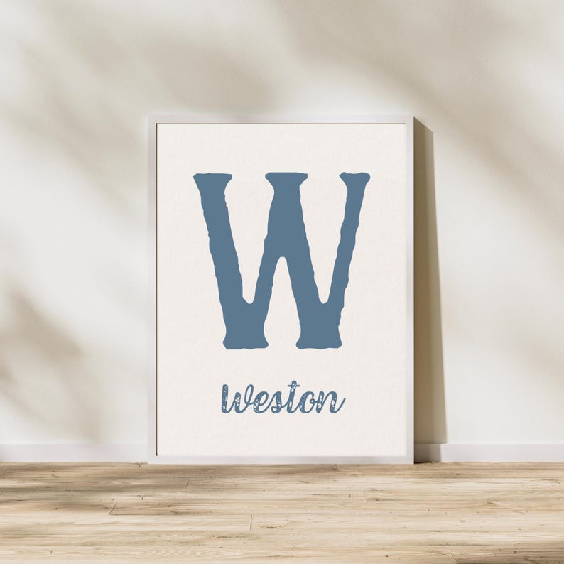K&ouml;nnte beinhalten: Ein wei&szlig;er gerahmter Druck mit einem gro&szlig;en blauen Buchstaben W und dem Namen Weston, der darunter in blau geschrieben ist.
