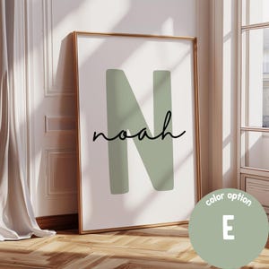 Puede incluir: Impresión enmarcada con el nombre "Noah" en una fuente elegante sobre una gran "N" verde salvia. La obra de arte se muestra en un marco dorado, con una etiqueta de opción de color en la esquina inferior derecha.