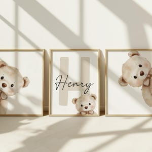 Puede incluir: Tres impresiones enmarcadas con un tema de guarder&iacute;a. Cada impresi&oacute;n presenta una ilustraci&oacute;n de un oso de peluche beige. La impresi&oacute;n central tiene el nombre "Henry" en escritura cursiva, con una gran letra "H" en el fondo.