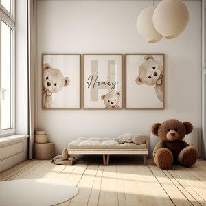 Puede incluir: Tres impresiones enmarcadas con ilustraciones de osos de peluche y el nombre "Henry". Un gran oso de peluche marr&oacute;n est&aacute; sentado en el suelo cerca de una cama peque&ntilde;a. La habitaci&oacute;n tiene suelo de madera clara y tonos neutros.