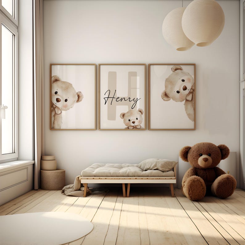 Puede incluir: Tres impresiones enmarcadas con ilustraciones de osos de peluche y el nombre "Henry". Un gran oso de peluche marr&oacute;n est&aacute; sentado en el suelo cerca de una cama peque&ntilde;a. La habitaci&oacute;n tiene suelo de madera clara y tonos neutros.