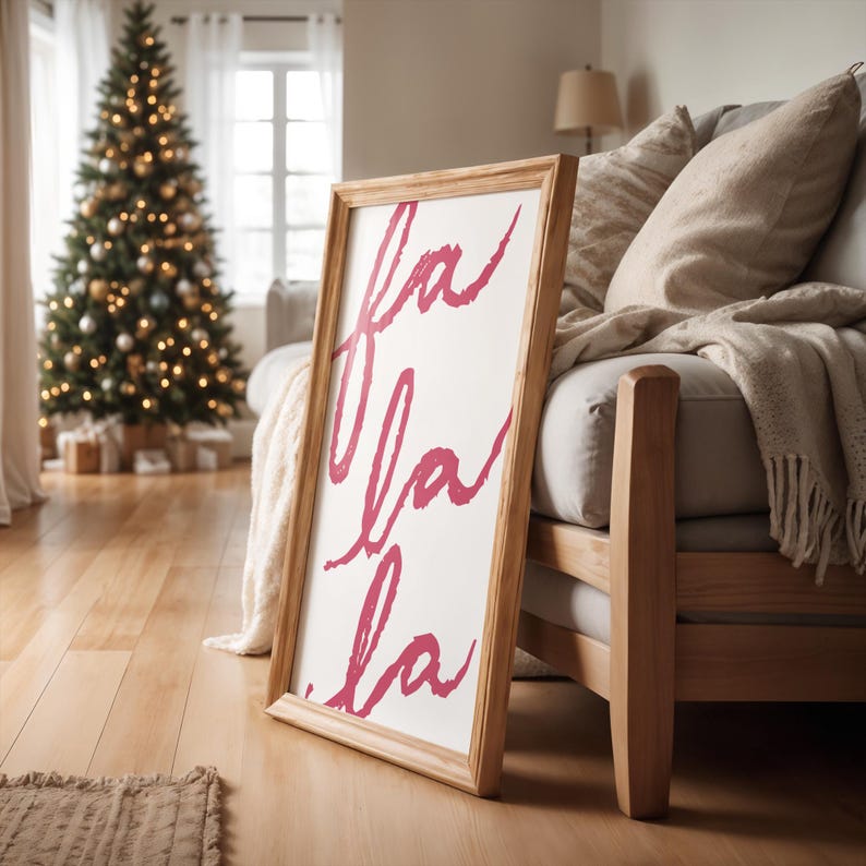 May include: A wooden framed sign with the words "fa la la" written in pink script on a white background.