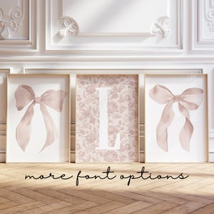 May include: Three framed art prints. Two prints feature a watercolor bow in shades of pink. The center print displays the letter "L" in white against a floral background. The phrase "more font options" is written in cursive at the bottom.