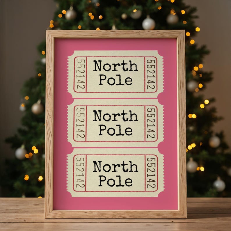 May include: Three vintage-style tickets with the text "North Pole" printed on them. The tickets are framed in a light wood frame and have a pink background.