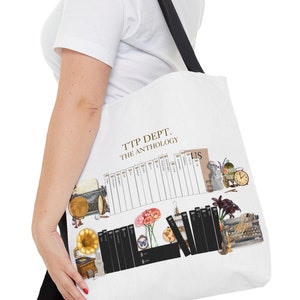 May include: White tote bag with black handles featuring a graphic design of a typewriter, books, flowers, and a gramophone. The text "TTP DEPT. THE ANTHOLOGY" is printed on the bag.